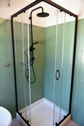 Cabina de dutxa tancada amb vidre, amb plat de roba i raig de mà.