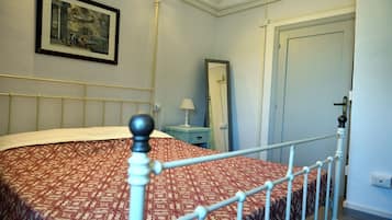 Una camera da letto con un letto, un comodino, una lampada, uno specchio e una porta.