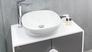 Un baño con un lavamanos blanco, un espejo y una toalla colgada en la pared.