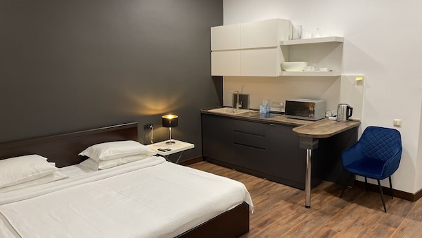 Una habitación de hotel moderna con cama, escritorio, silla y kitchenette.
