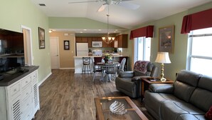 A living room with a sofa, coffee table, and a dining area with chairs and a table. - Beautiful Dog Friendly Home with Gas Golf Cart, BBQ Grill, & FREE WiFi! (The Villages)