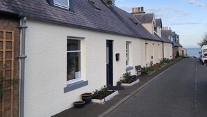 Une rangée de maisons blanches aux toits sombres, un ciel dégagé et une voiture garée dans la rue.