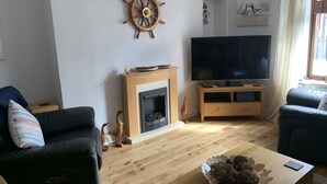 Un salon avec une cheminée, un téléviseur et deux canapés.