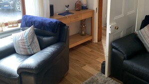 Un salon avec un canapé en cuir, une table basse en bois et une grande horloge murale.
