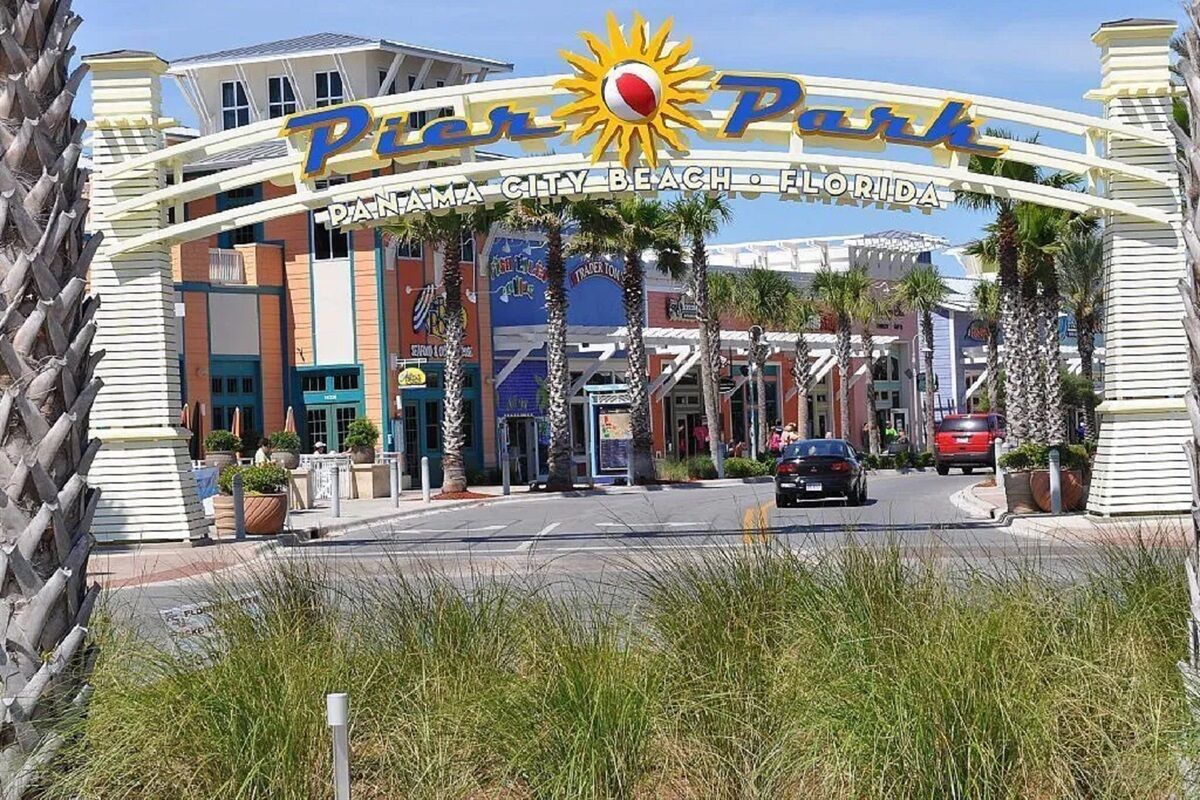 La entrada a Pier 70 en Panama City Beach, Florida, con un logo de sol y varios comercios y restaurantes a la vista.
