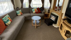 A compact living area with a sofa, a small round table, a television, and a fireplace.