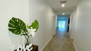 A hallway with a wooden console table, a large green leaf decoration, and a 'Love' sign. - Treasure Coast Retreat 3 bedroom duplex home (PORT ST LUCIE)