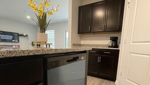 A modern kitchen with dark cabinetry, a granite countertop, and a dishwasher. - Treasure Coast Retreat 3 bedroom duplex home (PORT ST LUCIE)