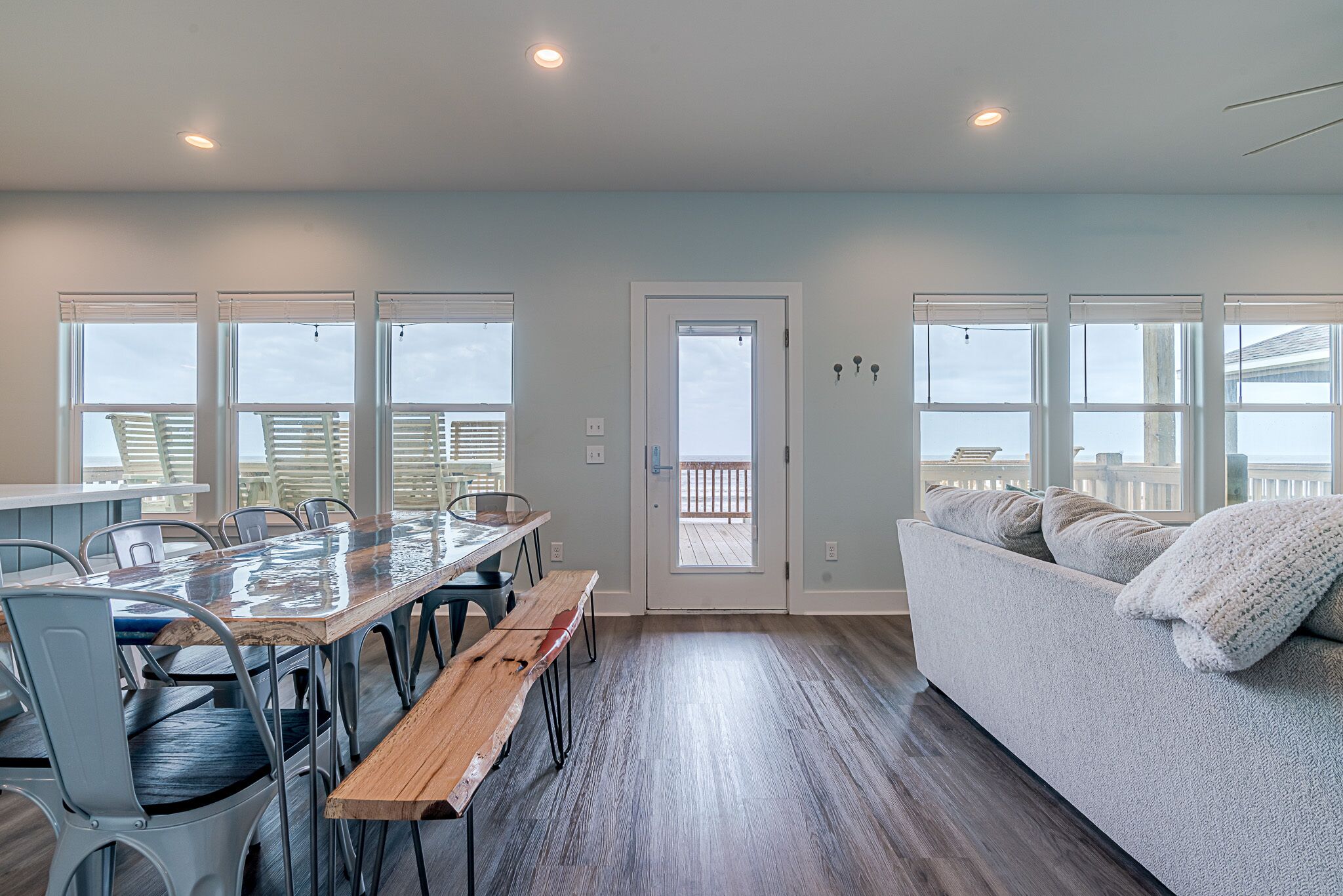Amplia habitación con una gran mesa de madera para comer, varias sillas, un sofá y una puerta que da a un balcón exterior.