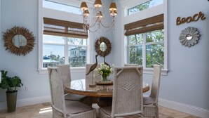 A dining area with wicker chairs, a glass table, and a chandelier.