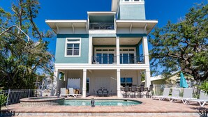A two-story house with a pool, outdoor seating, and a balcony.