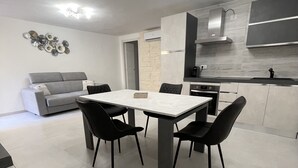 Una cocina moderna con zona de comedor, un sofá gris y una pequeña planta en maceta.