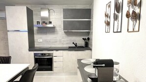 Cocina compacta con zona de comedor, que incluye una estufa moderna, lavamanos y un refrigerador pequeño.