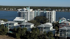 A coastal residential area with modern multi-story buildings, a clear view of the water, and a forested background.