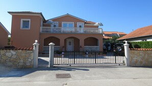 Une maison à deux étages avec un balcon, un mur en pierre et un portail en métal.