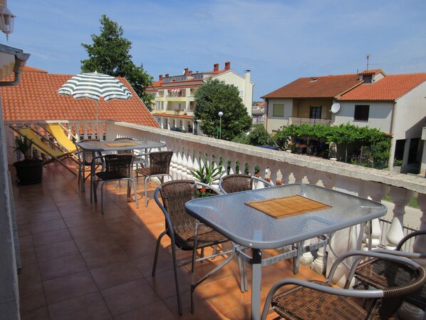 A terrace with outdoor seating, a small table, and a striped umbrella.