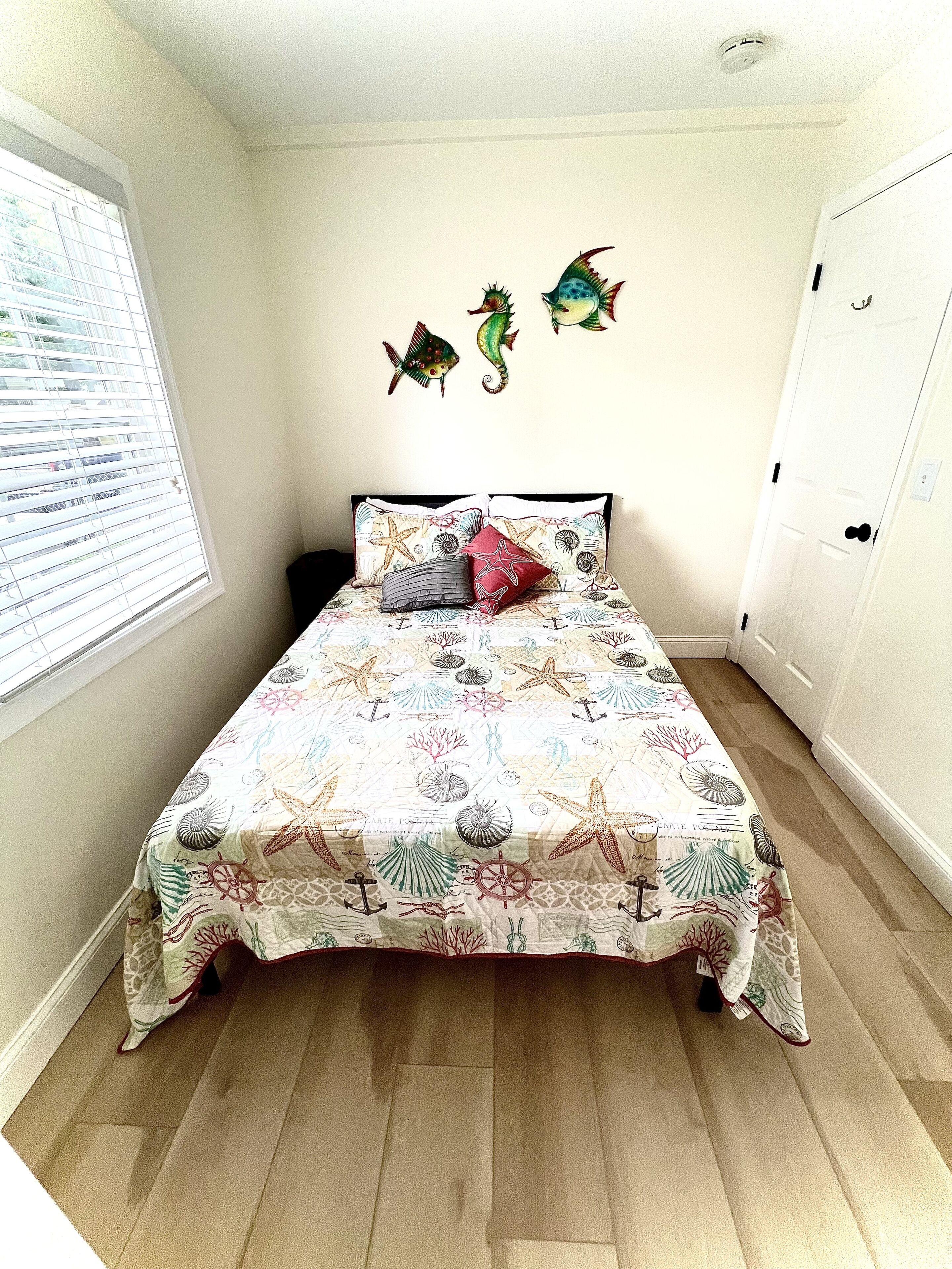 A bedroom with a bed, a window with blinds, and a door.