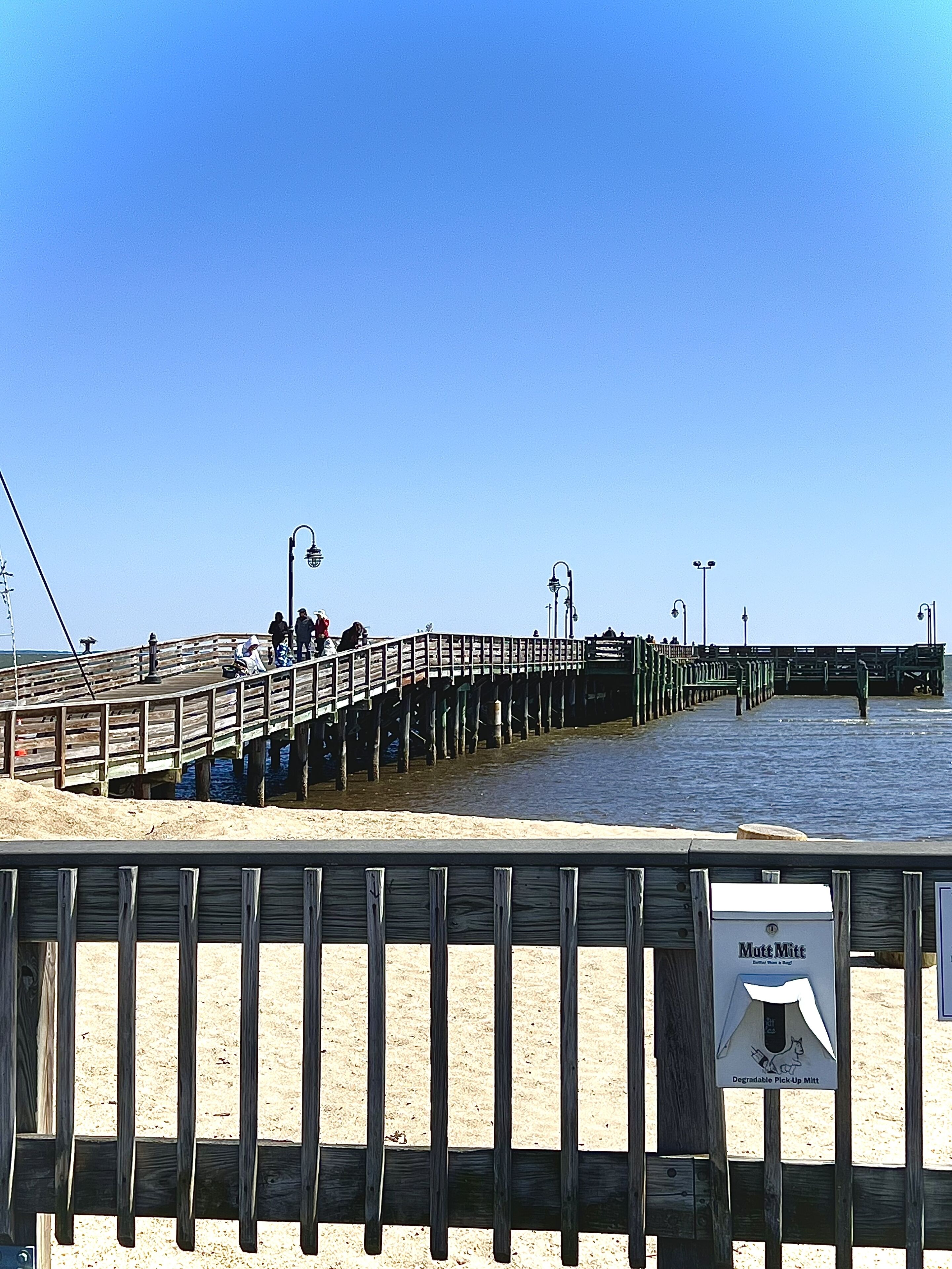 A wooden pier extending into the water with people walking along it.