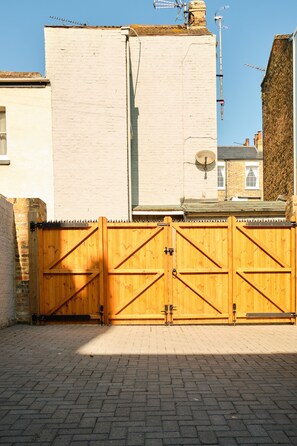A gated entrance with a brick pathway leading to a building with a white facade and a chimney. - Impeccable 6-bed House in Ramsgate, Harbour Views (Ramsgate)