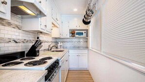 Uma cozinha compacta com armários brancos, micro-ondas e fogão.