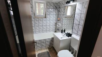 Een bad/douchecombinatie, handdoeken, zeep, shampoo