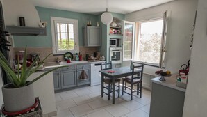 A kitchen with a dining table, grey cabinets, a potted plant, and a window. - Villa with pool at the foot of the Luberon (Maubec)