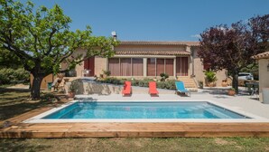 A house with a swimming pool, two red lounge chairs, and a garden. - Villa with pool at the foot of the Luberon (Maubec)