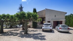A building with a garage, two parked cars, and a tree in the foreground. - Villa with pool at the foot of the Luberon (Maubec)