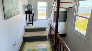 Eine Treppe mit Holzgeländer, Teppichstufen und Blick ins Freie durch ein Fenster.