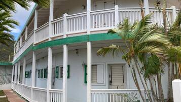 A two-story building with a balcony, white exterior, and green trim.