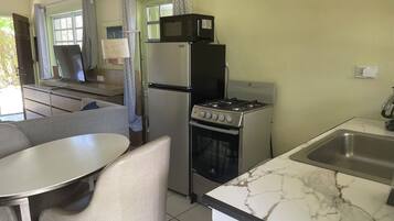 A compact kitchen with a refrigerator, microwave, stove, and sink.
