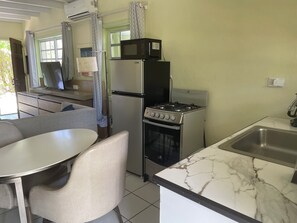 A compact kitchen with a refrigerator, microwave, stove, and sink. - Boundless Bliss Hotel (St. Thomas)