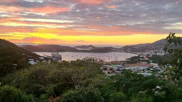 A coastal town with a view of the sea and boats, surrounded by hills and greenery.