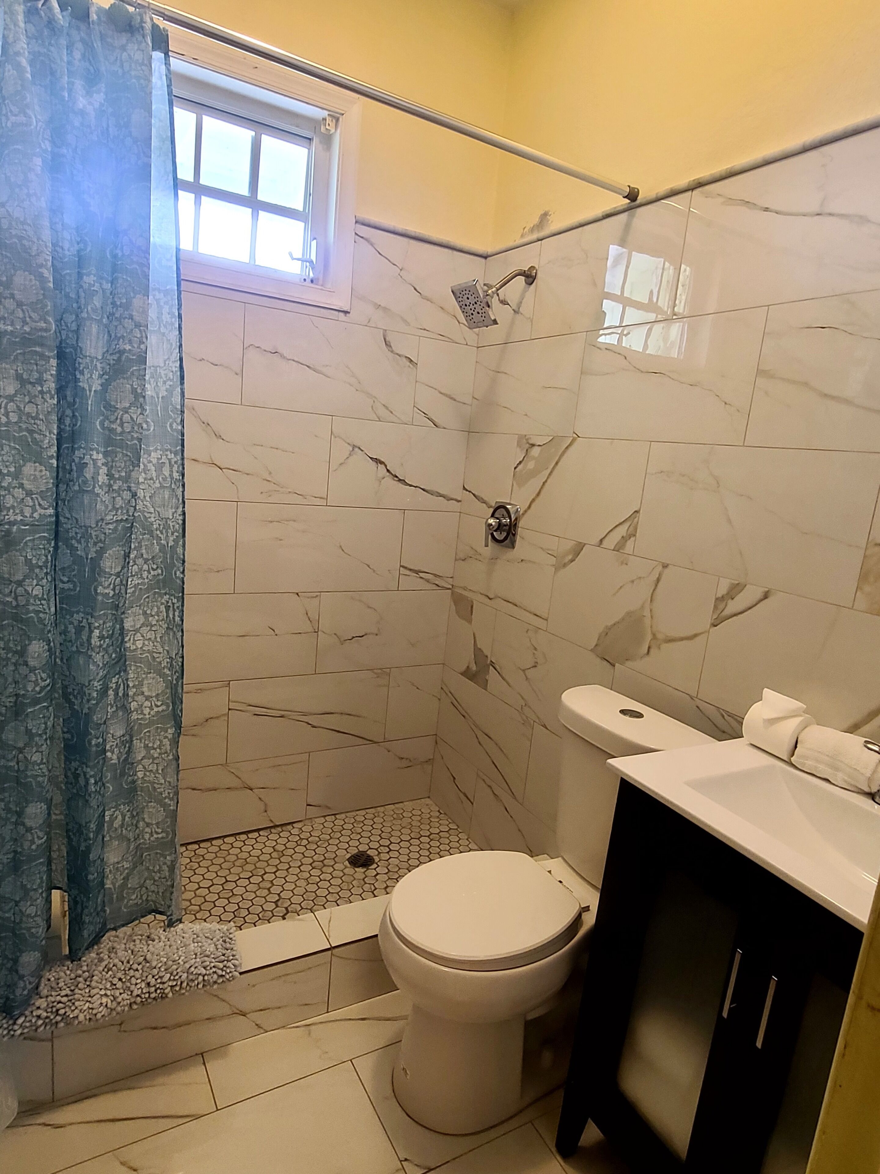 A bathroom with a shower, toilet, and sink.