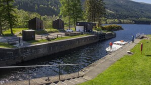 A lock system with a boat docked at the entrance, surrounded by grassy areas and wooden buildings. - Laggan Bothies (Spean Bridge)