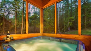 Un jacuzzi con revestimiento de madera y amplias ventanas que dan a un bosque.