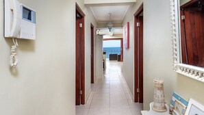A hallway with a telephone, a door, and a view of the sea.