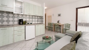 Ett kompakt bostadsutrymme med ett litet kök, en matplats och en sittgrupp.