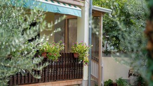 En bostadsbyggnad med en balkong, krukväxter och ett staket av trä.