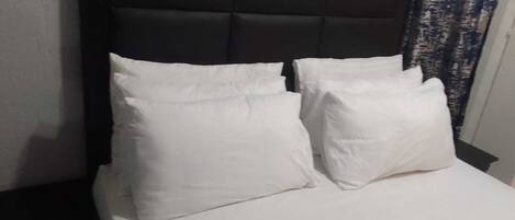 A bed with a dark headboard and white bedding.