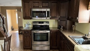 A kitchen with wooden cabinets, stainless steel appliances, and a granite countertop.