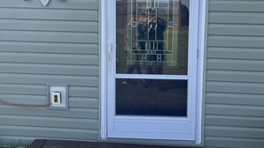 A house with a white window, a small outdoor light fixture, and a power outlet on the siding.