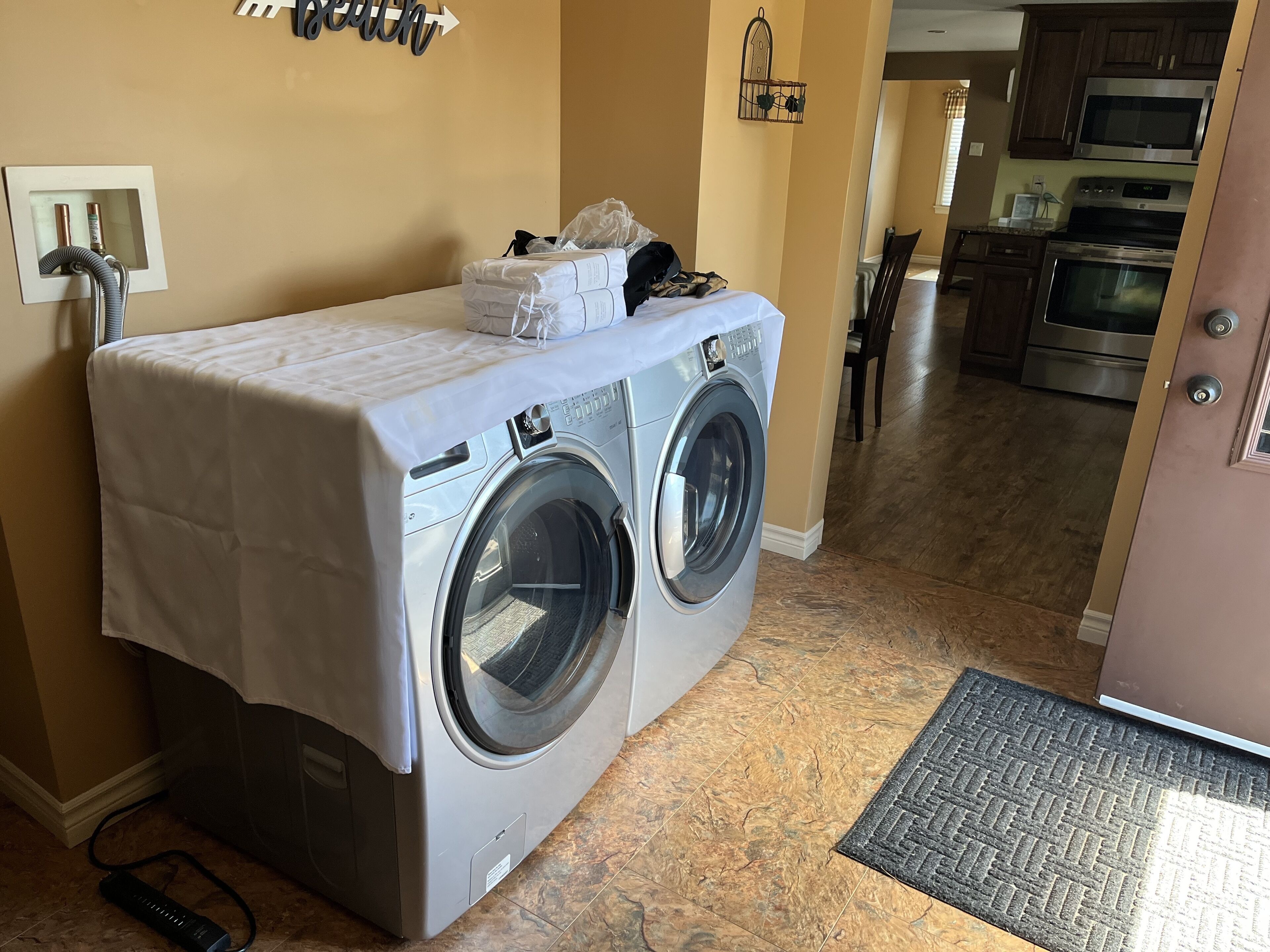 A compact laundry area with a washing machine and dryer, a power outlet, and a wall-mounted light fixture.