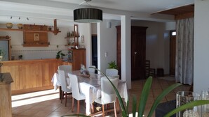 Una cocina amplia con armarios de madera, un comedor con mesa y sillas, y un ventanal que deja entrar luz natural.