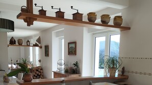 Una cocina amplia con armarios de madera, lavavajillas integrado y una isla grande con pileta. Hay estantes sobre la encimera con varios utensilios de cocina.