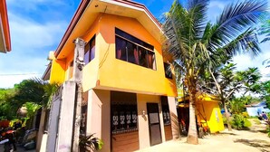 A two-story building with a yellow facade, large windows, and a gated entrance.
