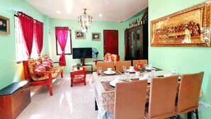 A dining area with a table set for four, a television, and a chandelier.