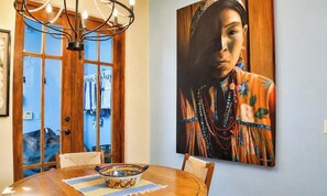 A dining area with a wooden table, chairs, a chandelier, and a large painting on the wall. - Spectacular Home Located steps from Lap Pool with Great Patio (Loreto)