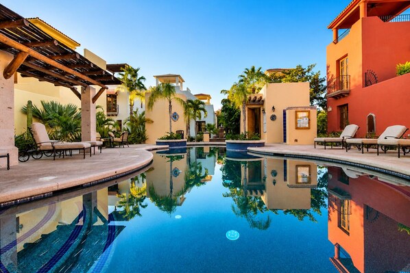 A pool area with lounge chairs, a reflection pool, and buildings with balconies. - Spectacular Home Located steps from Lap Pool with Great Patio (Loreto)