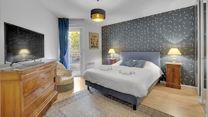 Ein Schlafzimmer mit einem Bett, Nachttischen, einem Fernseher und einer Wand mit Muster.
